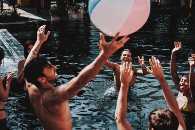 Grup arkadaşıyla genç gülümseyen havuzda eğleniyor. Genç mutlu insanlar iskambil birlikte ile renkli plaj topu içinde Açık Yüzme Havuzu. Arkadaşlar havuz partisinde. Yaz tatili kavramı