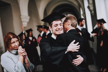 Sarılmak. Anne. Tebrikler. Öğrenci. Çalışmaları bitirmek. Üniversitesi. Mezun oldu. Mutlu. İyi bir ruh hali. İyi eğlenceler. Mimarisi. Mutluluk. İlişkiler. Diploma. Ayakta. Koridor. Anne. Baba. Oğlu.