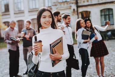 Kahve. Avlu. Kitaplar. Asyalı kız. Mutlu. Üniversitede ayakta. İyi bir ruh hali. Üniversitesi. Bilgi. Mimarisi. Mutluluk. İstihbarat. Diploma. Kutlama. Kampüs. Adam arkadaş. Öğrenciler.