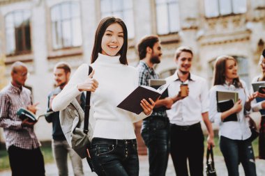 Üniversitede ayakta. Asyalı kız. Arkadaşlar. Avlu. Kitaplar. Mutlu. İyi bir ruh hali. Üniversitesi. Bilgi. Mimarisi. Mutluluk. İstihbarat. Diploma. Kutlama. Kampüs. Man.Students.