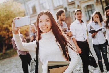 Selfi. Telefon. Ayakta University.Happy. İyi bir ruh hali. Üniversitesi. Bilgi. Avlu. Kitaplar. Mimarisi. Mutluluk. Asyalı kız. İstihbarat. Diploma. Kutlama. Kampüs. Adam arkadaş. Öğrenciler.