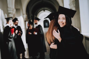 İki kız sarılmak. Mutluluk. Asyalı kız. İstihbarat. Diploma. Ayakta. Koridor. Üniversitesi. Elbiseler. Mezunu. İyi bir ruh hali. Üniversitesi. Neşeli. Kutlama. Kap. Kampüs. Adam bilgi. Harç kurulu.