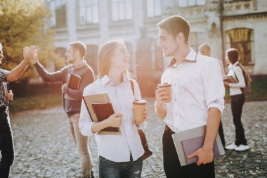 Kitap tutan. Üniversitede ayakta. İyi bir ruh hali. İstihbarat. Erkek ve kadın. Birlikte ayakta. Dışarıda. Güneşli bir gün. Öğrenciler. Arkadaşlar. Mutlu. Avlu. Kitaplar. Üniversitesi. Bilgi.
