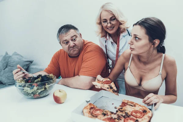 坐在胖子和年轻的厌食症女孩与食物 厌食症的女人 饮食和保健概念 和暴食症患者在一起健康的生活方式概念 超重男子 — 图库照片