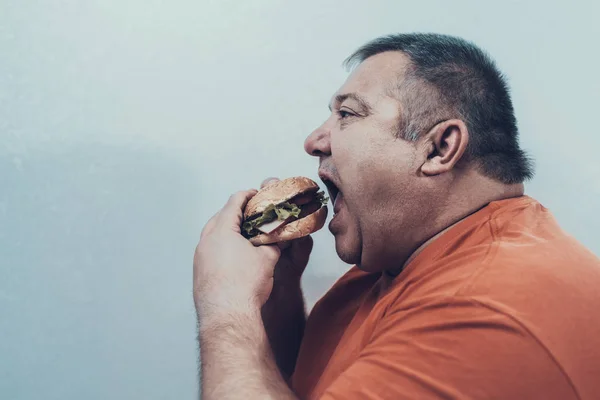 饥饿的脂肪垫在 Oranfe T恤与汉堡 和暴食症患者在一起不健康的生活方式概念 超重的人 不健康的食物 张开嘴 退出人类 饮食和保健概念 — 图库照片