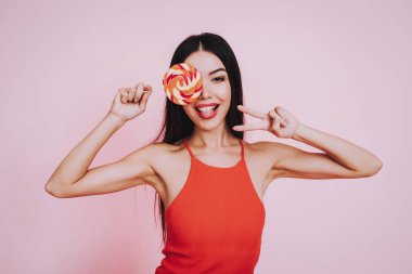 Kırmızı elbiseli kız. Pembe bir arka plan. Kutluyor kadınlar günü. Mart 8. Ayı olan kız. Gülümseyen kız. Mutlu bir kadın. Mutlu duygular. Uluslararası parti. Güzel kadın. Büyük lolipop. Lolipop kadınla