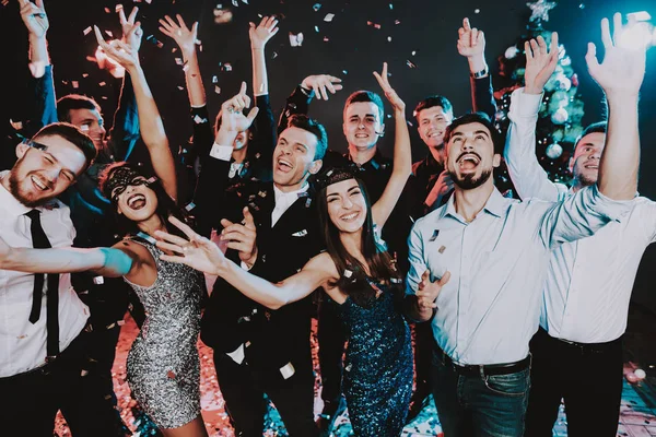 Smiling People Celebrating New Year on Party. Happy New Year. People Have Fun. Indoor Party. Celebrating of New Year. Young Woman in Dress. Young Man in Suit. Exited People. Hands Up.