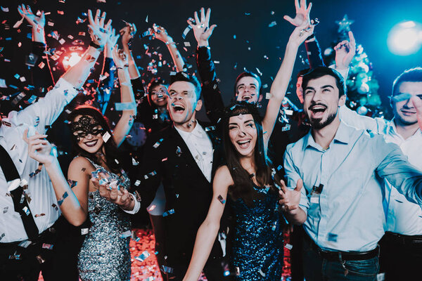 Smiling People Celebrating New Year on Party. Happy New Year. People Have Fun. Indoor Party. Celebrating of New Year. Young Woman in Dress. Young Man in Suit. Exited People. Hands Up.