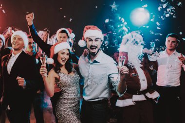 Yeni yıl partisi üzerinde dans mutlu gençler. Noel Baba. İnsanlar kırmızı kapaklar. Mutlu yeni yıl kavramı. Bir bardak şampanya. Yeni yıl kutlama. Elbiseli Genç kadın. Takım elbiseli erkekler.