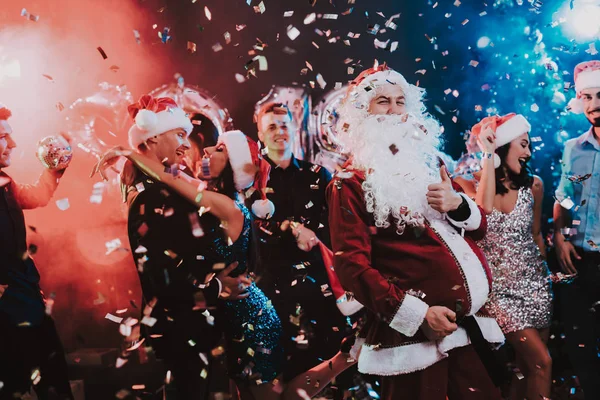 Man in Santa Claus Costume on New Year Party. Happy New Year. People Have Fun. Indoor Party. Celebrating of New Year. Young Women in Dresses. Young Men in Suits. Happy People. Man with White Beard.