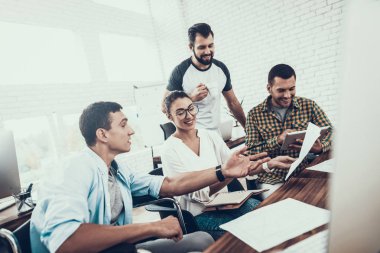 Genç işçiler Modern ofiste sohbet edelim. İş yerinde beyin fırtınası. Gülümseyen kadın. Adam tekerlekli sandalye üzerinde. Gülümseyen Yöneticisi. Office çalışmasında. Genç bir işçi. Meslektaşları ile oturan adam iletişim.