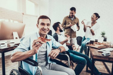 Gençler Pizza ile ofiste yemek. Office çalışmasında. Genç bir işçi. Oturan adam Pizza kutusu. Genç kız bardaklarda. Genç bir işçi. Molada Yöneticisi. Adam tekerlekli sandalye üzerinde.