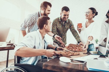 Gençler Pizza ile ofiste yemek. Office çalışmasında. Genç bir işçi. Oturan adam Pizza kutusu. Genç kız bardaklarda. Genç bir işçi. Molada Yöneticisi. Adam tekerlekli sandalye üzerinde.