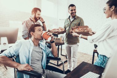 Gençler Pizza ile ofiste yemek. Office çalışmasında. Genç bir işçi. Oturan adam Pizza kutusu. Genç kız bardaklarda. Genç bir işçi. Molada Yöneticisi. Adam tekerlekli sandalye üzerinde.