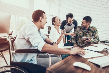 Genç işçiler Modern ofiste sohbet edelim. İş yerinde beyin fırtınası. Gülümseyen kadın. Adam tekerlekli sandalye üzerinde. Gülümseyen Yöneticisi. Office çalışmasında. Genç bir işçi. Meslektaşları ile oturan adam iletişim.