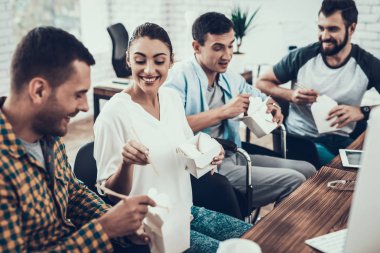 Gençler ofisinde Asya gıda ile yemek. Office çalışmasında. Genç bir işçi. Oturan adam Pizza kutusu. Genç kız bardaklarda. Genç bir işçi. Molada Yöneticisi. Adam tekerlekli sandalye üzerinde.