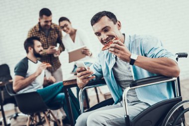 Gençler Pizza ile ofiste yemek. Office çalışmasında. Genç bir işçi. Oturan adam Pizza kutusu. Genç kız bardaklarda. Genç bir işçi. Molada Yöneticisi. Adam tekerlekli sandalye üzerinde.