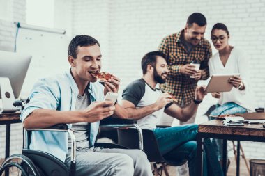 Gençler Pizza ile ofiste yemek. Office çalışmasında. Genç bir işçi. Oturan adam Pizza kutusu. Genç kız bardaklarda. Genç bir işçi. Molada Yöneticisi. Adam tekerlekli sandalye üzerinde.