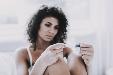Hamilelik testini güzel üzgün kadın iç çamaşırı yatakta oturup bakarak genç kadın. Hayal kırıklığına uğramış genç kız having problem. Kız Depressed hamilelik testi sonucu nedeniyle