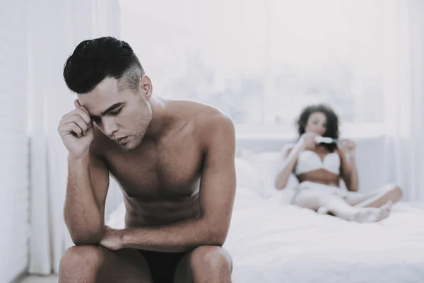 Sad Man Sitting next to Woman with Pregnancy Test. Young Unhappy Woman Looking at Pregnancy Test. Beautiful Woman Sitting on Bed in Underwear. Man Depressed because of Result of Pregnancy Test
