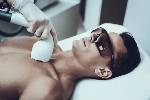 Young Man in Spa Salon for Laser Hair Removal. Guy in Beauty Salon. Modern Cosmetology. Proffesional Cosmetologist. Doctor with Laser Epilator. Men\'s Beauty Concept. Man in Glasses.