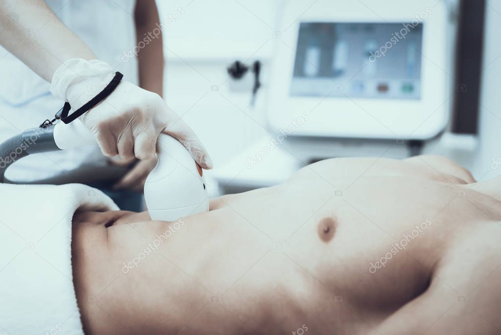 Young Man in Spa Salon for Laser Hair Removal. Guy in Beauty Salon. Modern Cosmetology. Proffesional Cosmetologist. Doctor with Laser Epilator. Men's Beauty Concept. Man in Glasses.