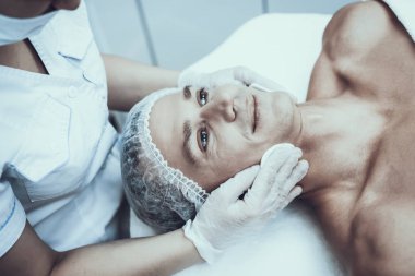 Spa salonda masaj temizlik için genç adam. Güzellik Salonu adam. Modern kozmetik. Profesyonel güzellik uzmanı. Beyaz önlük doktor. Erkek güzellik kavramı. Cilt Bakımı ve temizliği.