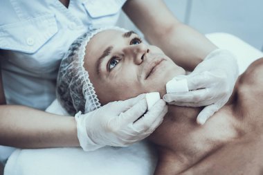 Spa salonda masaj temizlik için genç adam. Güzellik Salonu adam. Modern kozmetik. Profesyonel güzellik uzmanı. Beyaz önlük doktor. Erkek güzellik kavramı. Cilt Bakımı ve temizliği.