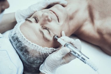 Spa Salon Lazer epilasyon için genç adam. Güzellik Salonu adam. Modern kozmetik. Profesyonel güzellik uzmanı. Doktor lazer epilatör ile. Erkek güzellik kavramı. Tıbbi donatımı.