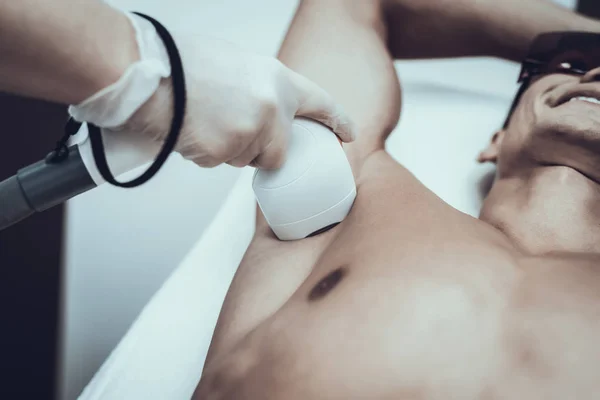 Young Man in Spa Salon for Laser Hair Removal. Guy in Beauty Salon. Modern Cosmetology. Proffesional Cosmetologist. Doctor with Laser Epilator. Men\'s Beauty Concept. Man in Glasses.