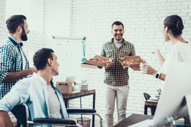 Gençler Pizza ile ofiste yemek. Office çalışmasında. Genç bir işçi. Oturan adam Pizza kutusu. Genç kız bardaklarda. Genç bir işçi. Molada Yöneticisi. Adam tekerlekli sandalye üzerinde.