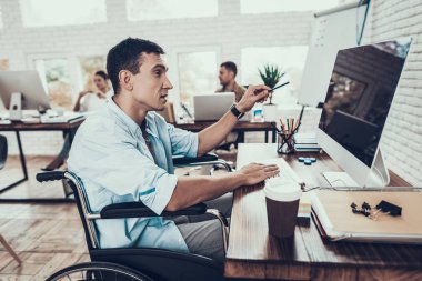 Tekerlekli sandalye ofiste bilgisayar üzerinde çalışan adam. Genç adam adam tekerlekli sandalye üzerinde devre dışı. Kurtarma ve sağlık kavramları. Office çalışmasında. Genç bir işçi. Oturan adam adam bilgisayar ile.