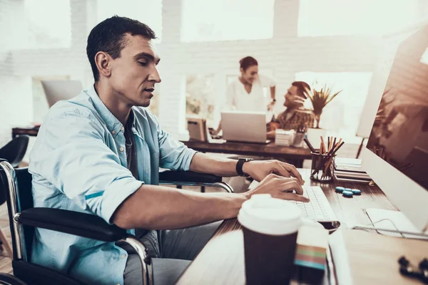 Man on Wheelchair Working on Computer in Office. Disabled Young Man. Man on Wheelchair. Recovery and Healthcare Concepts. Teamwork in Office. Young Worker. Sitting Man. Man with Computer.