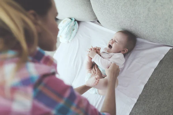 Dikkat Anne Ağlayan Bebeğin Kanepede Swaddles Mutlu Anne Giysi Hafif — Stok fotoğraf