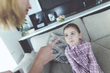 Anne azarı üzgün güzel çocuk kapalı. Modern oturma odasında rahat kanepede oturan beyaz kızı suçlu ve Anne küfür bakarak hissediyor. Aile ilişki kavramı
