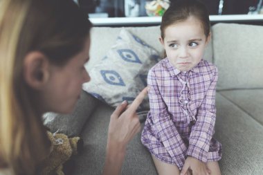 Genç Anne azarı üzgün güzel çocuk kapalı. Modern oturma odasında rahat kanepede oturan beyaz kızı suçlu ve Anne küfür bakarak hissediyor. Aile ilişki kavramı