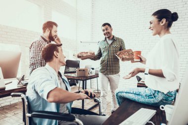 Gençler Pizza ile ofiste yemek. Office çalışmasında. Genç bir işçi. Oturan adam Pizza kutusu. Genç kız bardaklarda. Genç bir işçi. Molada Yöneticisi. Adam tekerlekli sandalye üzerinde.