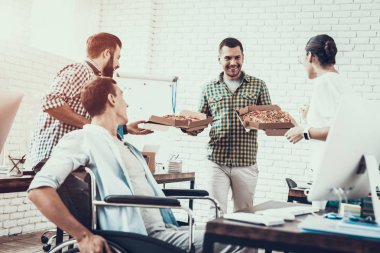 Gençler Pizza ile ofiste yemek. Office çalışmasında. Genç bir işçi. Oturan adam Pizza kutusu. Genç kız bardaklarda. Genç bir işçi. Molada Yöneticisi. Adam tekerlekli sandalye üzerinde.