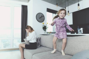 Kız sahip eğlenceli atlama Divan Anne ne zaman üzgün. Parlak Modern oturma odasında büyük rahat kanepede karışıklık çevrede çocuk. Anne hayal kırıklığına Holding başkanı geliyor