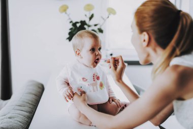 Mutlu anne kaşık ile sevimli çocuk evde beslenir. Bright salon şirin aç yürümeye başlayan çocuk sahip odaya masada otururken annesi ile. Annelik ve çocukluk kavramı