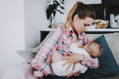 Genç kapalı küçük bebek emzirme anne. Mutlu portre? oturma odasında kanepede oturan ve sevimli sevimli çocuk diz Holding aucasian anne. Ebeveynlik ve çocukluk kavramı