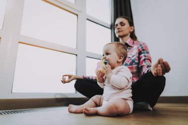 Şirin bebek oynarken annesi Meditates katta. Portre tatlı sevimli güzel beyaz çocuk oyuncak elinde tutan ve ağız oturma odasında. Annelik ve çocukluk kavramı