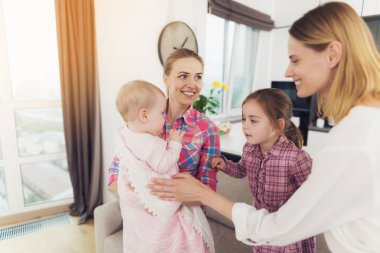 Bebek bakıcısı ve anne çocuk ile kapalı oyun. Beyaz mutlu dadı Holding bebek el ve iş kadını Anne ve kızı sarılma çocuk parlak oturma odasında üzerinde gülümseyen.