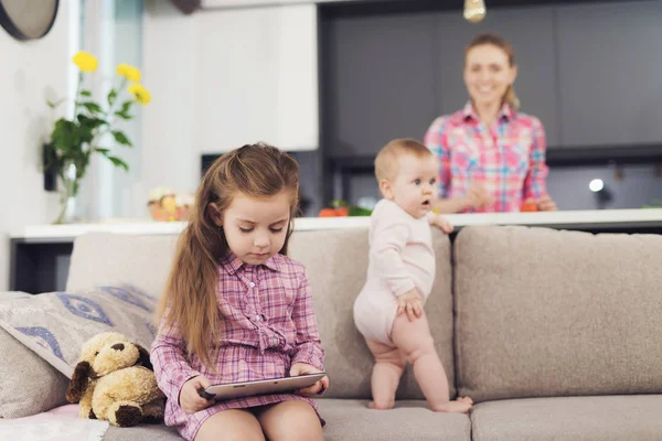 可爱的白种人儿童在家里使用平板电脑 年长的长头发的女孩拿着垫在手显示小工具屏幕可爱的婴儿休息在舒适的沙发在明亮的房间在家里 — 图库照片