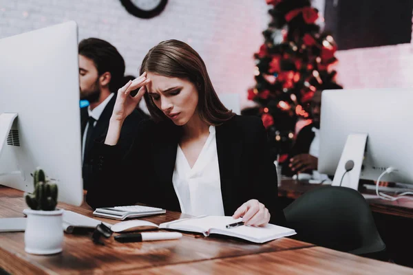 Tired People Working in Office on New Year Eve. Christmas Tree in Office. Computer on Desk. Working Businessman. Upset Businesswoman. Celebrating of New Year. Using Digital Device.