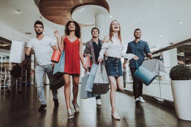 Paketleri ile alışveriş merkezinde alışveriş arkadaş şirket. Alışveriş kavramı. Kırmızı elbiseli kız. Kadın beyaz gömlekli. Siyah Cuma kavramı. Çıktıktan gençler. Modern pazar. Elinde paketleri.
