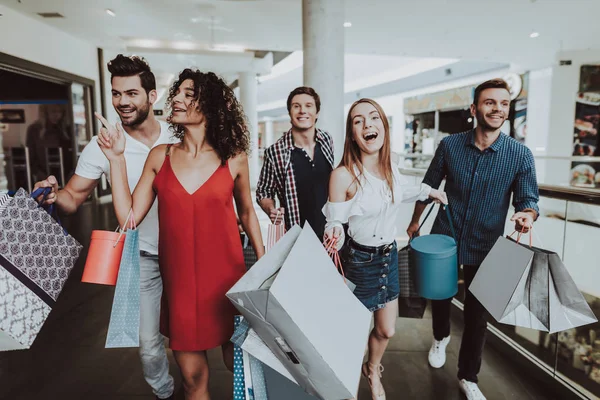 Paketleri ile alışveriş merkezinde alışveriş arkadaş şirket. Alışveriş kavramı. Kırmızı elbiseli kız. Kadın beyaz gömlekli. Siyah Cuma kavramı. Çıktıktan gençler. Modern pazar. Elinde paketleri.