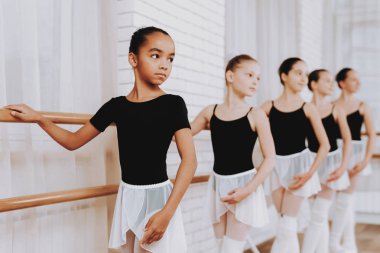 Genç kızların kapalı grubunun bale eğitimi. Klasik bale. Kız balerin Tutu. Kapalı eğitim. Şirin dansçılar. Performans salonunda. Pratik dans. Kızlar beyaz elbiseler.