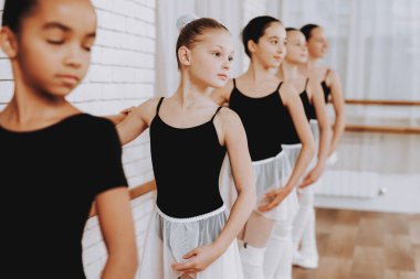 Genç kızların kapalı grubunun bale eğitimi. Klasik bale. Kız balerin Tutu. Kapalı eğitim. Şirin dansçılar. Performans salonunda. Pratik dans. Kızlar beyaz elbiseler.