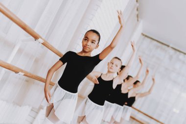 Genç kızların kapalı grubunun bale eğitimi. Klasik bale. Kız balerin Tutu. Kapalı eğitim. Şirin dansçılar. Performans salonunda. Pratik dans. Kızlar beyaz elbiseler.